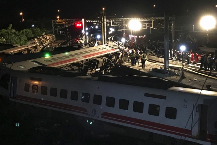 Petugas penyelamat berkumpul di lokasi tergulingnya kereta di Lian, Taiwan Utara, Ahad (21/10). Sejumlah orang tewas dan ratusan meninggal akibat kecelakaan.