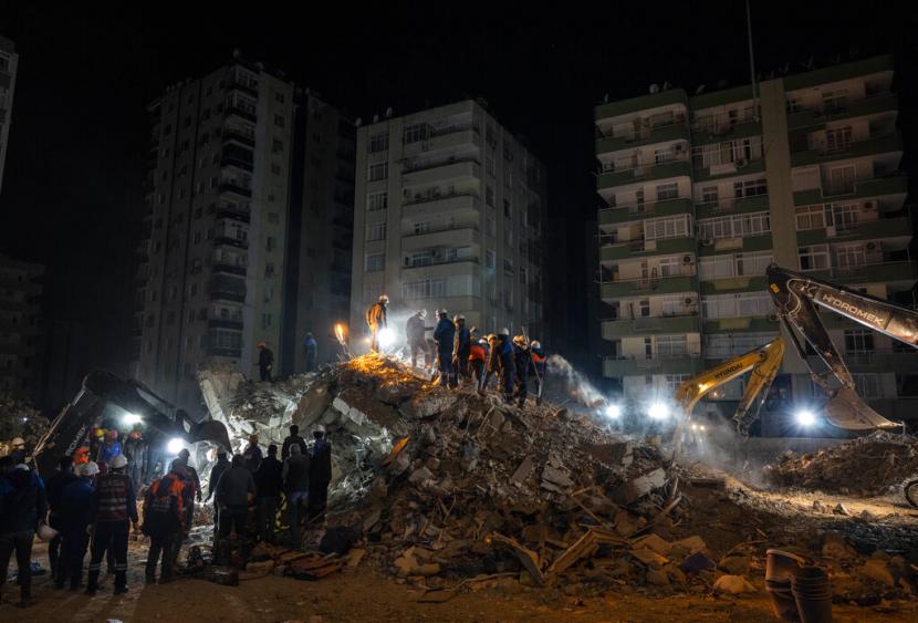 Petugas penyelamat mencari jenazah dan korban gempa di bangunan yang runtuh di Adana, Turki tenggara, Jumat, 10 Februari 2023. Sekitar 12.000 bangunan di Turki telah runtuh atau mengalami kerusakan serius, menurut menteri lingkungan dan tata kota Turki, Murat Kurum.