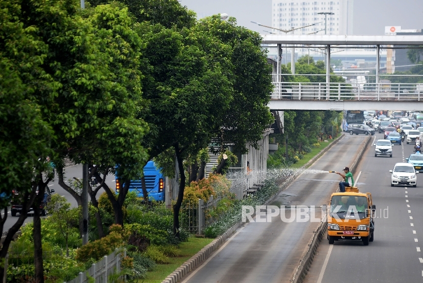 Petugas pertamanan dan pemakaman menyiram tanaman jalur hijau dengan mengunakan truk penyiram di kawasan Matraman, Jakarta, Kamis (9/2). 