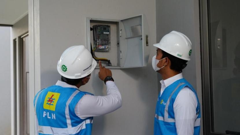 Petugas PLN memeriksa kWh meter milik pelanggan rumah tangga.