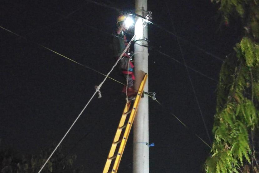 Petugas PLN sedang memperbaiki kabel listrik setelah bus pengangkut rombongan haji tersangkut kabel tersebut. 