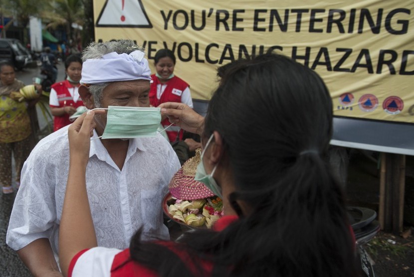 Petugas PMI memasangkan masker kepada warga di Pasar Desa Menanga yaitu kawasan rawan bencana Gunung Agung, Karangasem, Bali, Kamis (23/11). 