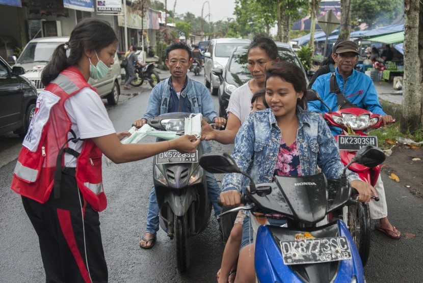 Relawan membagikan masker kepada pengendara di Pasar Desa Menanga yaitu kawasan rawan bencana Gunung Agung, Karangasem, Bali.