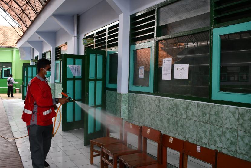 Petugas PMI menyemprotkan cairan disinfektan di lingkungan SMPN 10 Kota Madiun, Jawa Timur, Jumat (11/2/2022). Pekan ini, Kota Madiun berstatus PPKM level 4.