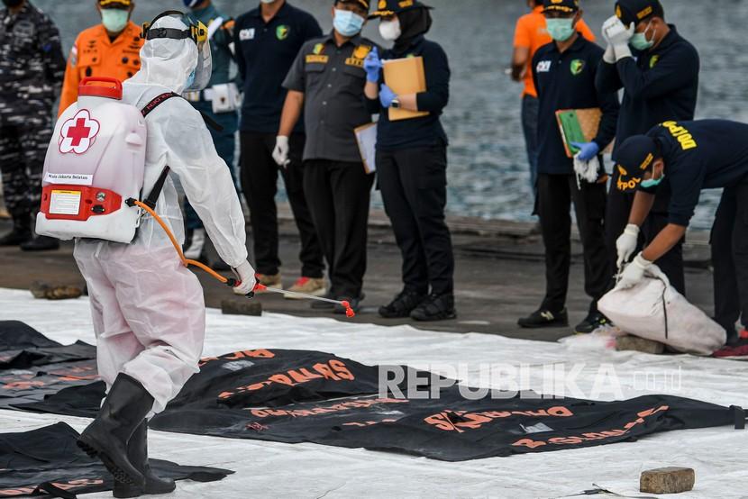 Petugas PMI menyemprotkan cairan disinfektan ke kantong jenazah berisi objek temuan dari lokasi jatuhnya pesawat Sriwijaya Air nomor penerbangan SJ 182 rute Jakarta-Pontianak di Dermaga JICT, Tanjung Priok, Jakarta Utara, Jumat (15/1/2021). Pada hari ketujuh operasi pencarian puing dan korban Sriwijaya Air SJ182, penyelam Basarnas menemukan 13 kantong yang merupakan bagian tubuh korban. 