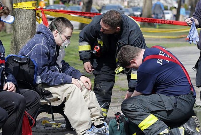 Petugas PMK memastikan kondisi seorang korban selamat dalam insiden ledakan bom di dekat garis finis Maraton Boston 2013, Senin 15 April, 2013