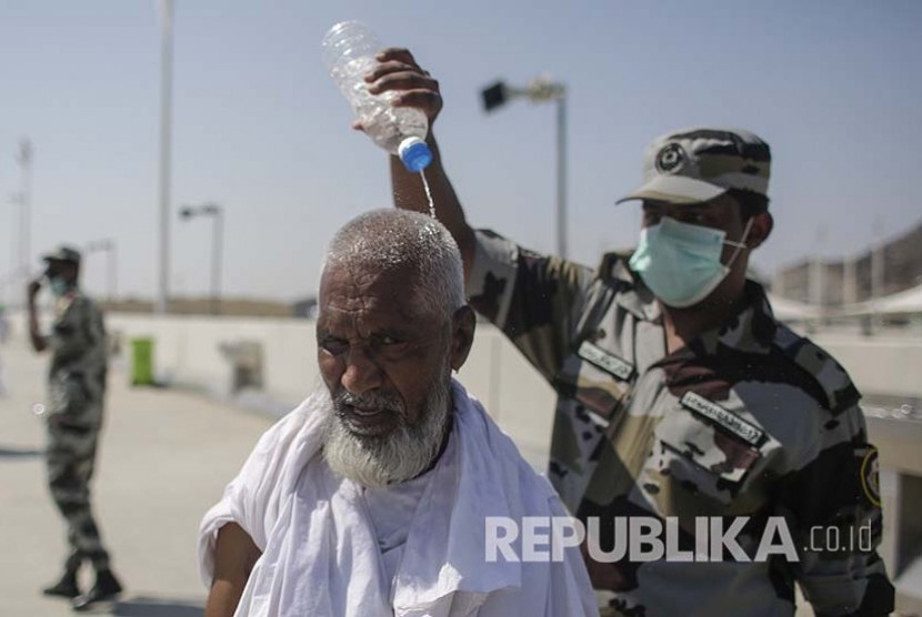 Ilustrasi. Petugas polisi Arab Saudi menyiramkan air ke kepala seorang jamaah haji untuk mengurangi sengatan panas matahari di Jamarat, Senin (12/9). Gelombang Panas Landa Arab Saudi, Suhu Makkah dan Madinah 49 Derajat Celsius