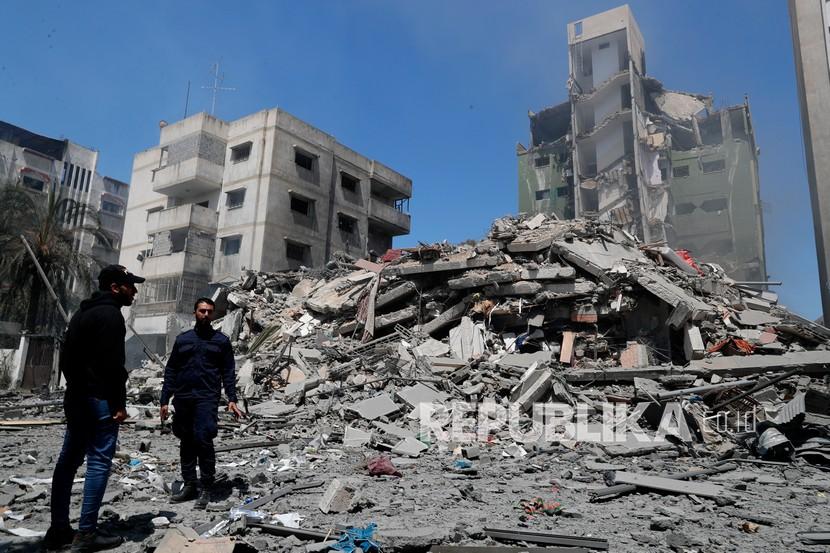  Petugas polisi Hamas berjaga-jaga di tengah puing-puing bangunan perumahan Yazegi yang dihancurkan oleh serangan udara Israel, di Kota Gaza, Ahad (16/5).