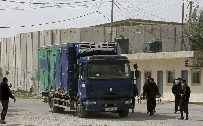 Petugas polisi Hamas menjaga truk yang berisi kiriman vaksin virus corona Sputnik V Rusia di perlintasan perbatasan Kerem Shalom, di Rafah, Jalur Gaza, Rabu, 17 Februari 2021. 