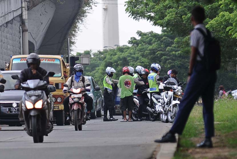 Petugas Polisi Lalu Lintas memberhentikan kendaraan roda dua di Jalan Basuki Rahmat, Jakarta Timur, Rabu (7/5).