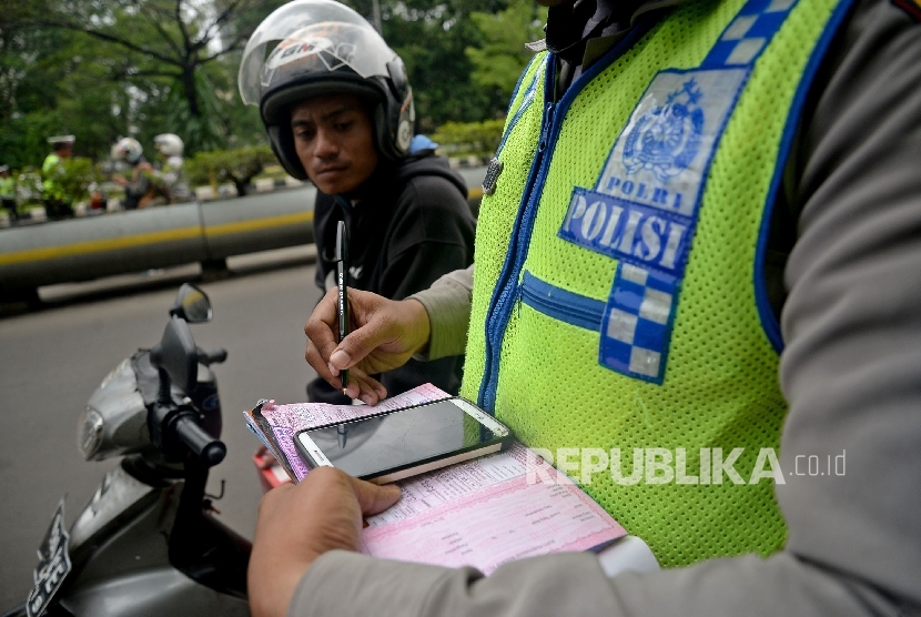 Petugas polisi melakukan penindakan terhadap pelanggar lalu lintas dengan mengunakan sistem E-Tilang saat razia kendaraan bermotor di Kawasan Kemayoran, Jakarta, Rabu (11/1).