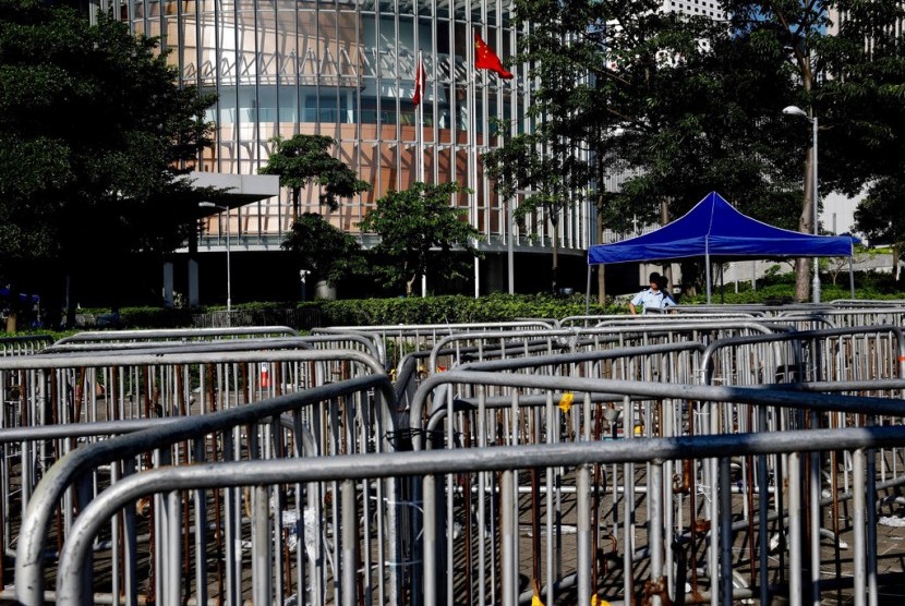 Petugas polisi melihat ke arah penghalang di sekitar gedung dewan di Hong Kong, Jumat (14/6). Suasana kembali tenang di Hong Kong setelah berhari-hari digelar protes oleh aktivis HAM dan mahsiswa menentang UU yang membiarkan tersangka diadili di pengadilan daratan Cina. 