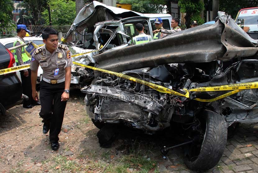  Petugas polisi memeriksa kondisi kendaraan Lancer IVO yang dikendarai putra Ahmad Dhani, AQJ yang ringsek akibat kecelakaan di Tol Jagorawi, Ahad (8/9). (Republika/Yasin Habibi)