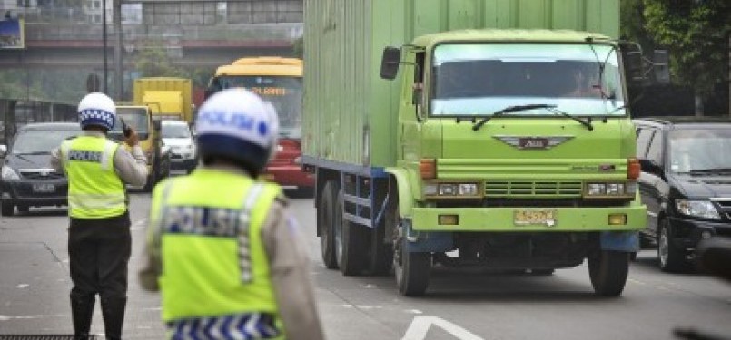 Petugas Polisi mengatur lalu lintas truk di pintu masuk Tol, jalan S. Parman, Kebon Jeruk, Jakarta Barat.