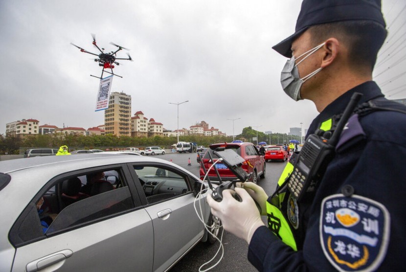 Petugas polisi mengoperasikan drone yang membawa QR code dekat pintu tol di Shenzen, Guangdong, China. Penggunaan QR code membantu polisi mendaftar kendaraan yang kembali ke Shenzen tanpa harus langsung kontak dengan pengemudi hingga meminimalisir penyebaran corona.