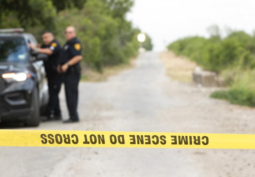 Petugas polisi San Antonio menjaga tempat kejadian Selasa, 28 Juni 2022, di San Antonio di mana puluhan migran ditemukan tewas di sebuah trailer-traktor pada hari Senin setelah ditinggalkan dalam panas terik. Ini adalah tragedi terbaru yang merenggut nyawa para migran yang diselundupkan melintasi perbatasan dari Meksiko ke AS.