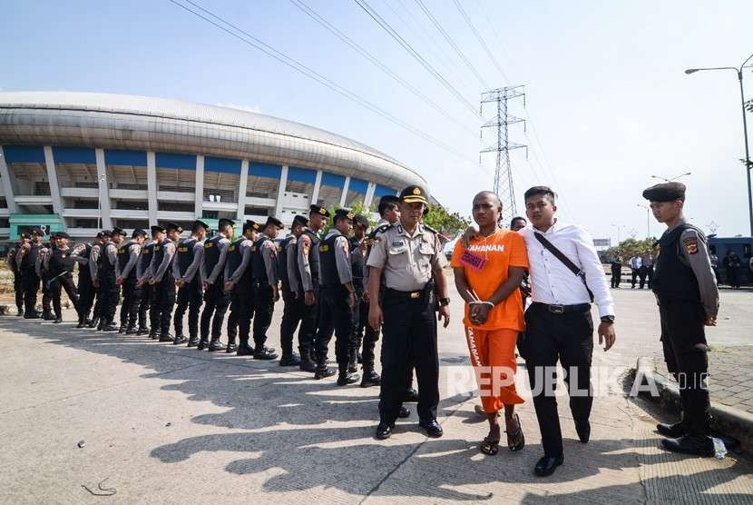 Petugas Polrestabes Bandung membawa seorang tersangka saat menggelar rekonstruksi pengeroyokan yang dilakukan oleh oknum bobotoh terhadap seorang suporter Persija, Haringga Sirla, di Stadion Gelora Bandung Lautan Api (GBLA), Bandung, Jawa Barat, Rabu (26/9). 