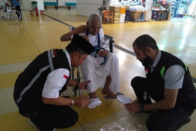 Petugas PPIH Arab Saudi memasangkan sandal untuk Dirah, seorang jamaah asal NTB yang mengklaim berusia 120 tahun di Bandara KAIA Jeddah, Selasa (31/7).