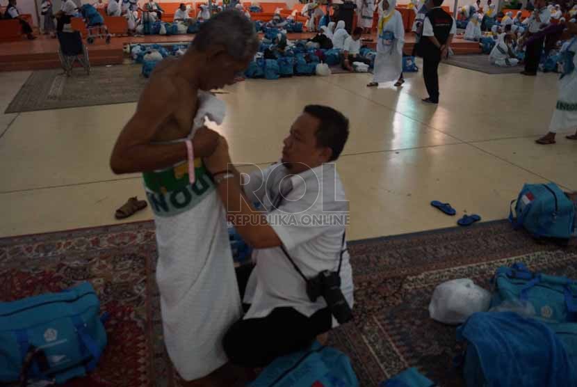 petugas PPIH Daker Jeddah, memakaian kain ihram ke salah satu jamaah haji Kloter 39 Embarkasi Solo di Plaza Bandara Internasional King Abdul Aziz, Jeddah, Selasa (16/9) malam waktu arab saudi. Sejak Senin (15/9) (Republika/Zaky Alhamzah)