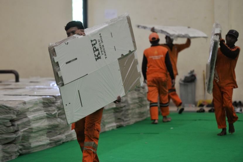 Petugas Prasarana dan Sarana Umum (PPSU) membantu memindahkan kotak dan bilik suara Pemilu 2024 ke Gelanggang Olah Raga Remaja Matraman, Jakarta Timur. Pasal 25 poin e PKPU melarang pemilih bawa ponse