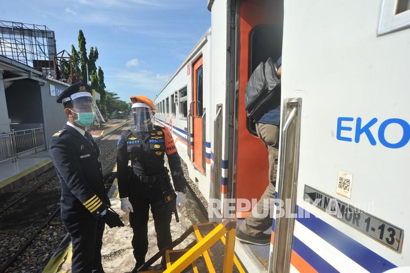 Petugas PT KAI bersama anggota kepolisian memantau Kereta Api Sibinuang sebelum berangkat, di Stasiun Tabing, Padang, Sumatera Barat, Sabtu (1/8/2020). PT KAI Divre II Sumbar kembali membuka perjalanan kereta api rute Padang - Naras (Pariaman) dengan memberlakukan protokol COVID-19 di antaranya penumpang diwajibkan menggunakan masker dan diimbau memakai pakaian lengan panjang serta menjaga jarak.