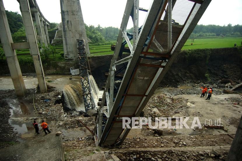 Petugas PT KAI memeriksa jembatan rel Kereta Api (KA) yang ambruk di Dukuh Timbang, Desa Tonjong, Brebes, Jawa Tengah, Selasa (12/1/2021). Jembatan sepanjang 50 meter dengan tinggi 22 meter yang menghubungkan Jakarta-Yogyakarta-Surabaya via jalur Selatan tersebut ambruk akibat diterjang banjir Sungai Glagah.