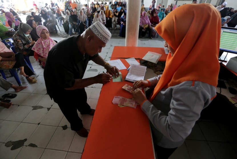 Petugas PT. Pos Indonesia melayani pensiunan PNS dan TNI/Polri mengambi gaji dan Tunjangan Hari Raya (THR) di Banda Aceh, Aceh, Senin (3/6/2019). 