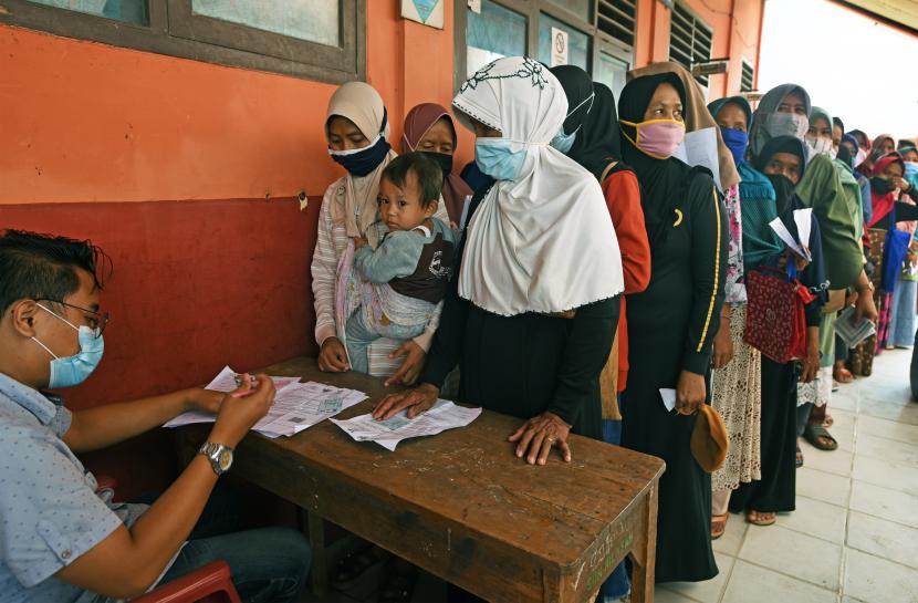 Petugas PT POS (kiri) mendata identitas warga penerima manfaat saat penyaluran bantuan sosial tunai (BST) untuk keluarga terdampak pandemi di halaman SD Negeri Kilasah, di Kasemen, Serang, Banten, Sabtu (13/2/2021). Dinsos Provinsi Banten mencatat terdapat 315.250 KK akan mendapat BST mulai Januari hingga April 2021 sebesar Rp300 ribu per-KK perbulan.