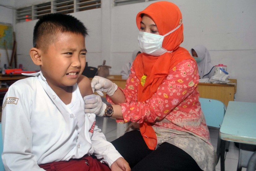 Petugas Puskesmas Sindangbarang Bogor memberikan imunisasi campak Rubella kepada siswa di SD Insan Kamil, Kota Bogor, Jawa Barat, Rabu (9/8). 