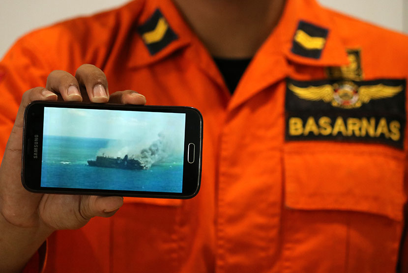 Petugas SAR menunjukkan foto KM Mutiara Sentosa I yang terbakar, di Posko Evakuasi KM Mutiara Sentosa I di Gapura Surya Nusantara, Pelabuhan Tanjung Perak, Surabaya, Jawa Timur, Sabtu (20/5).