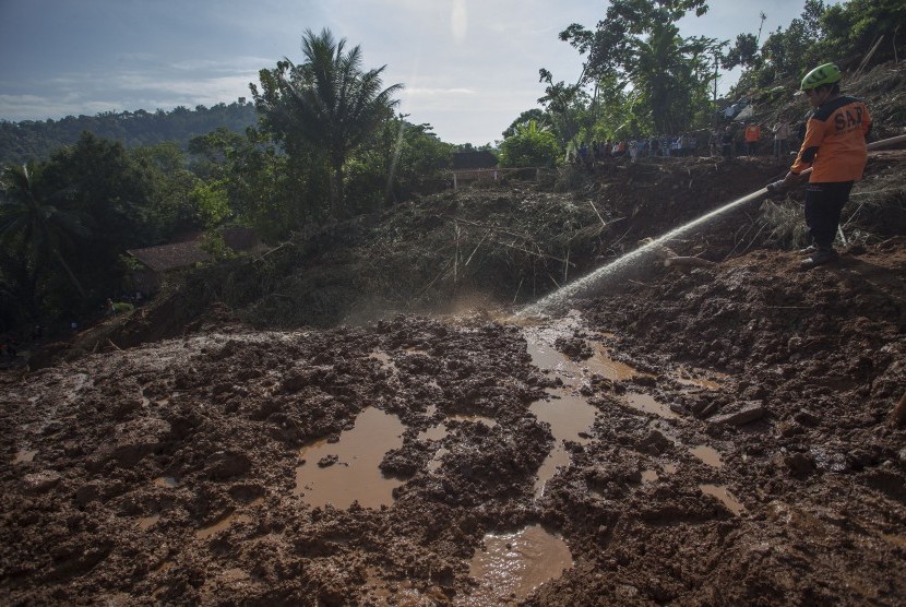 Petugas SAR menyemprotkan air ke material longsor guna mempermudah pencarian korban longsor yang diduga tertimbun tanah di Caok, Loano, Purworejo, Jawa Tengah, Rabu (22/6).