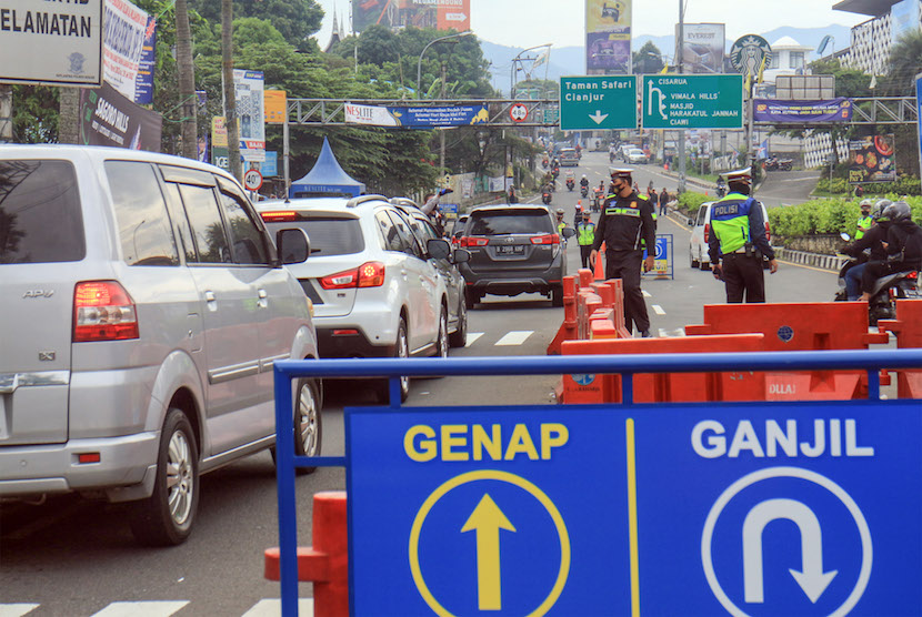Petugas Sat Lantas Polres Bogor dan petugas Dishub Kabupaten Bogor mengarahkan kendaraan wisatawan saat penyekatan kendaraan nomor polisi ganjil genap di jalur wisata Puncak, Gadog, Kabupaten Bogor.