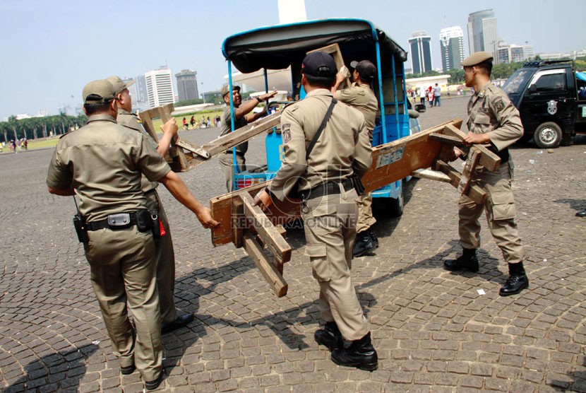   Petugas Satpol PP bersama Petugas UPT Monas, TNI dan polisi menertibkan para pedagang kaki lima (PKL) di kawasan Tugu Monas, Jakarta Pusat, Rabu (30/7). (Republika/Yasin Habibi)