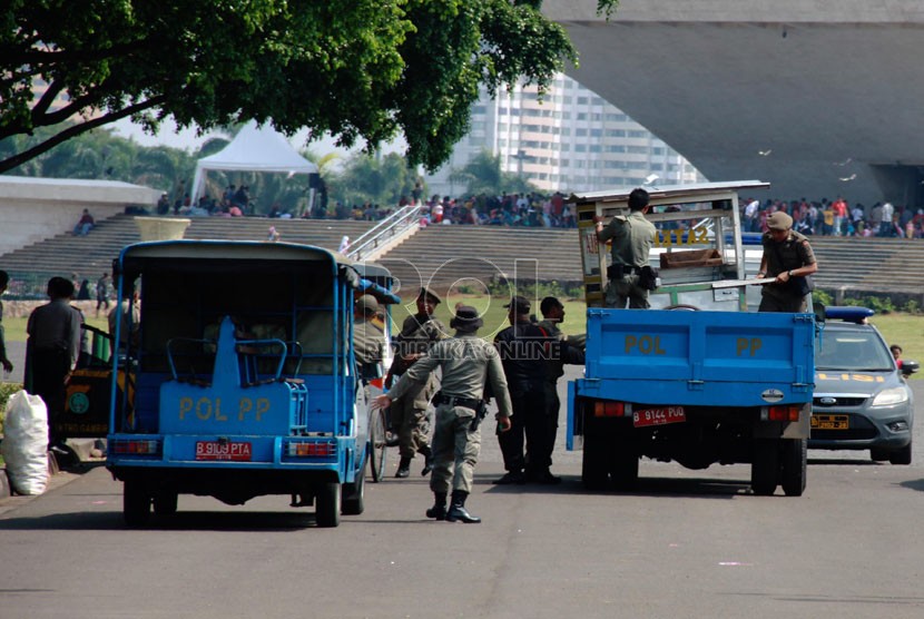   Petugas Satpol PP bersama Petugas UPT Monas, TNI dan polisi menertibkan para pedagang kaki lima (PKL) di kawasan Tugu Monas, Jakarta Pusat, Rabu (30/7). (Republika/Yasin Habibi)