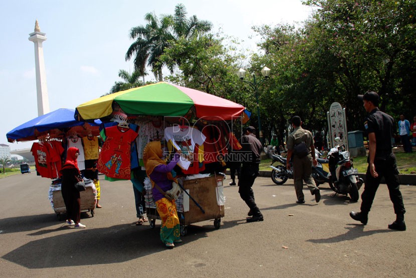   Petugas Satpol PP bersama Petugas UPT Monas, TNI dan polisi menertibkan para pedagang kaki lima (PKL) di kawasan Tugu Monas, Jakarta Pusat, Rabu (30/7). (Republika/Yasin Habibi)