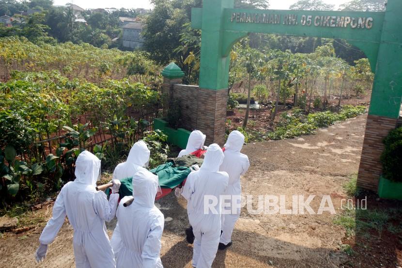 Petugas Satpol PP Kabupaten Bogor menggunakan pakaian hazmat di pemakaman.