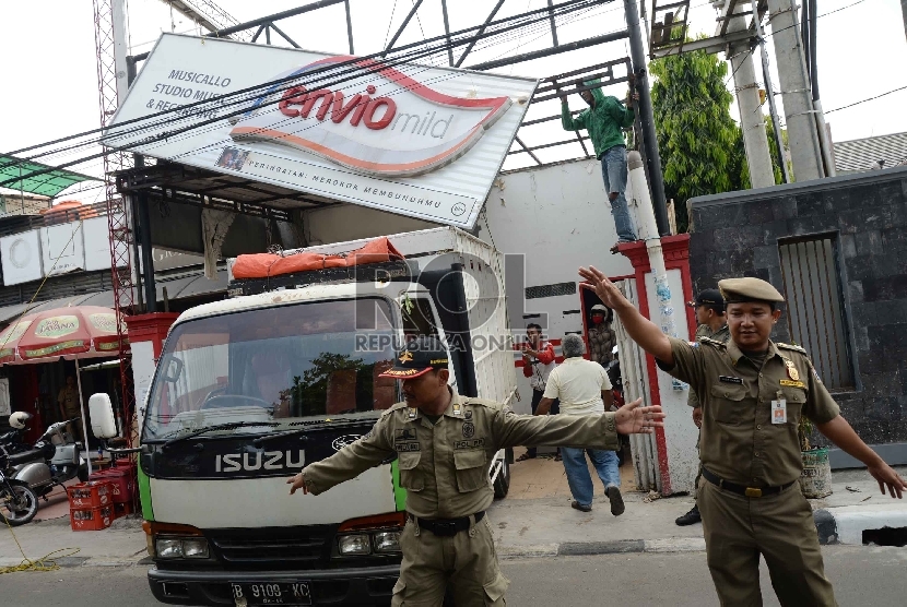 Petugas satpol pp melakukan penurunan reklame rokok di Kawasan Tegalparang, Jakarta Selatan, Rabu (18/11).