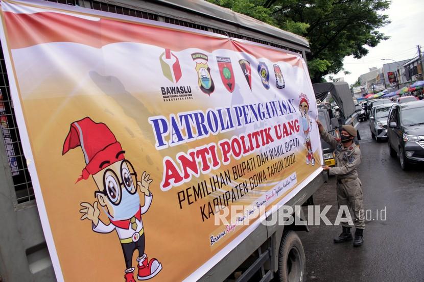 Petugas Satpol PP memasang spanduk pada truk yang digunakan untuk patroli pengawasan anti politik uang di Kabupaten Gowa, Sulawesi Selatan, Sabtu (5/12/2020). Patroli gabungan tersebut untuk mengantisipasi terjadinya praktik politik uang jelang pilkada Kabupaten Gowa pada 9 Desember 2020. 