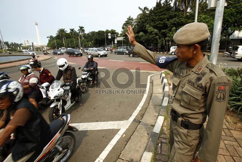  Petugas Satpol PP membantu mengatur lalu lintas  di sekitar Bundaran Patung Kuda, Jakarta Pusat, Senin (4/2).   (Republika/Adhi Wicaksono)