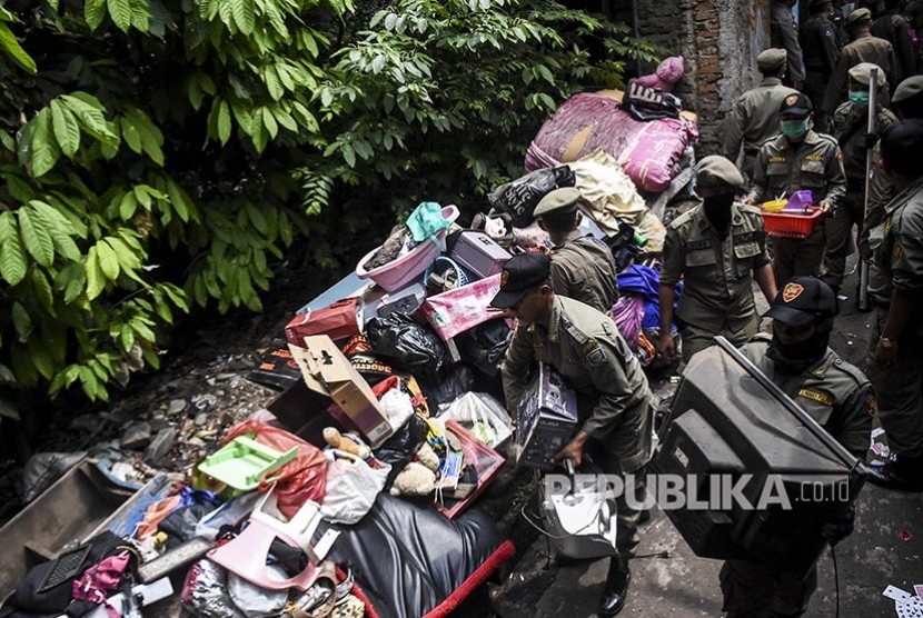 Petugas Satpol PP memindahkan  barang milik warga saat penggusuran permukiman Tamansari, Kota Bandung, Kamis (12/12). 