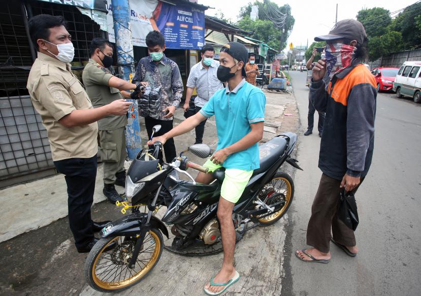 Petugas Satpol PP memberhentikan pengendara motor yang tidak menggunakan masker saat digelar razia penggunaan masker di Pondok Aren, Tangerang Selatan, Banten, Kamis (10/2/2022). Razia dilakukan bertujuan untuk menekan penyebaran penularan COVID-19, dimana Kota Tangerang Selatan merupakan daerah yang penyebaran dan penularannya cukup tinggi. 