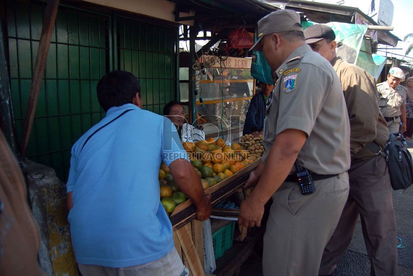  Petugas Satpol PP menertibkan lapak pedagang buah yang berjualan di Pasar Minggu, Jakarta Selatan, Rabu (6/8). (Republika/Raisan Al Farisi)