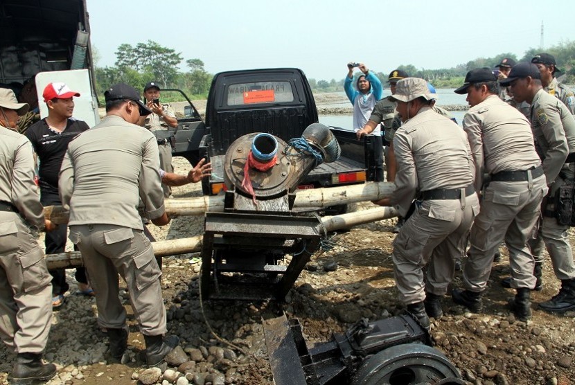 Petugas satpol PP mengangkat mesin dua mekanik penyedot pasir saat merazia penambangan pasir liar/ilegal di bantaran Sungai Brantas, Tulungagung, Jawa Timur, Kamis (22/10). 