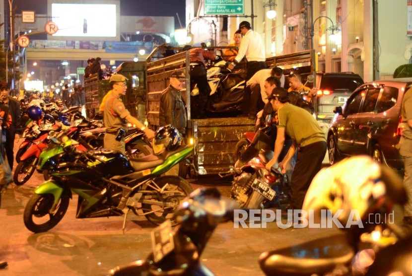 Petugas Satpol PP mengangkut sepeda motor yang parkir sembarangan pada malam takbiran, di Alun-alun Kota Bandung. (Ilustrasi)