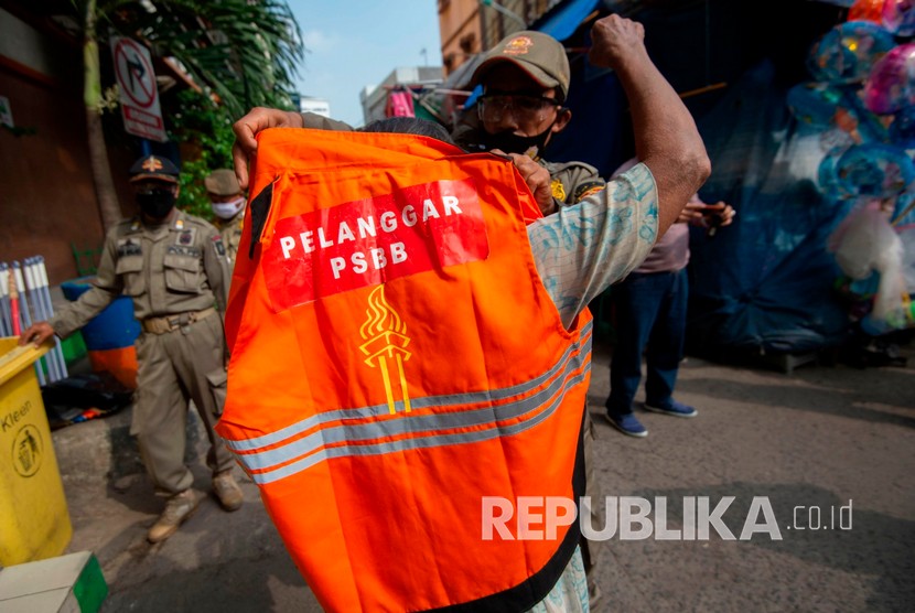 Petugas Satpol PP mengenakan rompi khusus kepada pelanggar aturan pembatasan sosial berskala besar (PSBB) 
