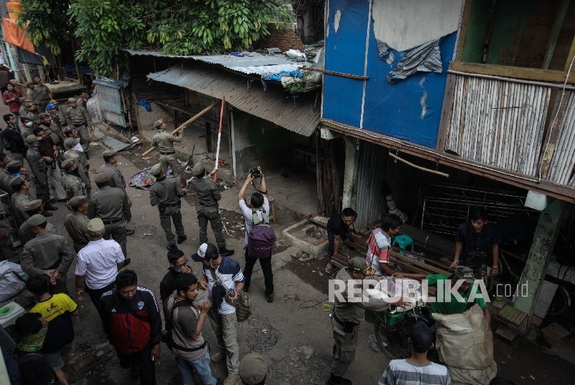 Petugas Satpol PP merobohkan sebuah rumah saat penggusuran di pemukiman proyek normalisasi Sungai Ciliwung, Bukit Duri, Jakarta, Rabu (28/9).