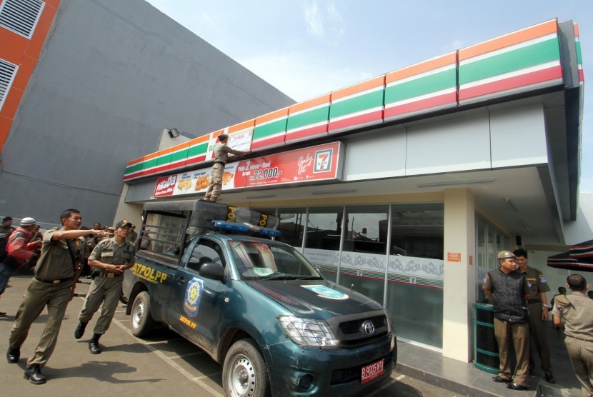 Petugas Satpol PP Tangsel melakukan penyegelan mini market Seven Eleven di kawasan Gaplek, Pamulang, Tangerang Selatan, Selasa (23/7).  