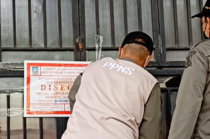 Petugas Satuan Pamong Praja (Satpol PP) menyiapkan lembar segel lapangan futsal yang dibangun tanpa IMB di Kemayoran, Jakpus.