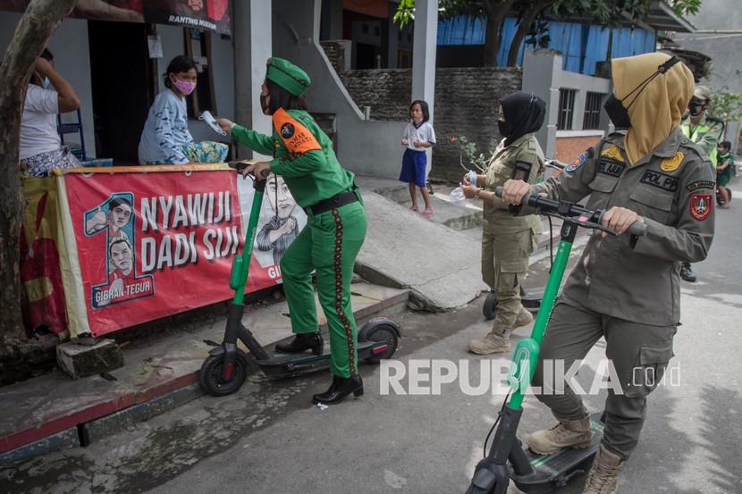 Petugas Satuan Polisi Pamong Praja (Satpol PP) dan Linmas menaiki skuter listrik saat melakukan Sosialisasi Protokol Kesehatan di Kampung Nusukan, Banjarsari, Solo, Jawa Tengah. Satpol PP Solo mengimbau kepada para pelaku usaha agar tidak menerima anak yang mengenakan seragam sekolah memasuki tempat usahanya. Sebab, sesuai Surat Edaran (SE) Wali Kota tentang PPKM level 2, anak sekolah diwajibkan langsung pulang setelah selesai kegiatan pembelajaran tatap muka (PTM).