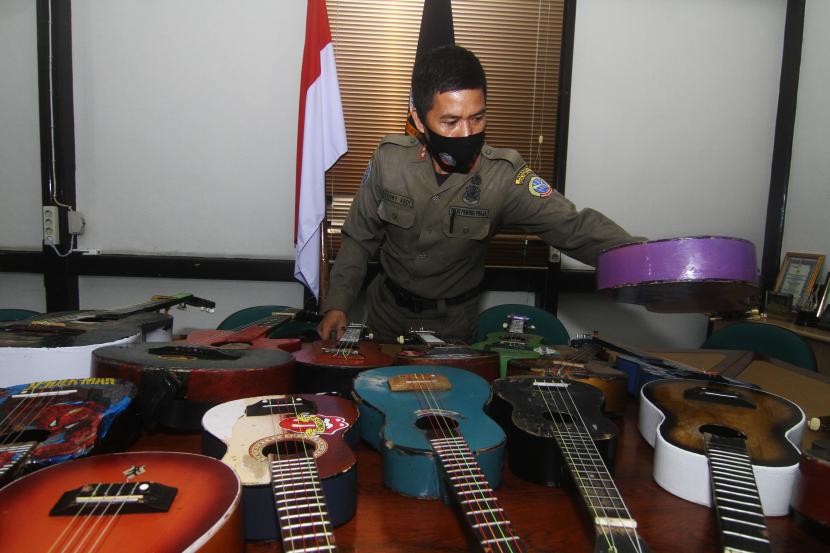 Petugas Satuan Polisi Pamong Praja (Satpol PP) Kota Pontianak memperlihatkan belasan alat musik petik hasil razia pengamen saat rilis di Mako Satpol PP Kota Pontianak, Kalimantan Barat, Senin (7/6/2021). Belasan alat musik petik berupa ukulele dan gitar tersebut merupakan hasil penjaringan dari pengamen di perempatan jalan yang telah meresahkan pengguna jalan dan mengganggu ketertiban umum.